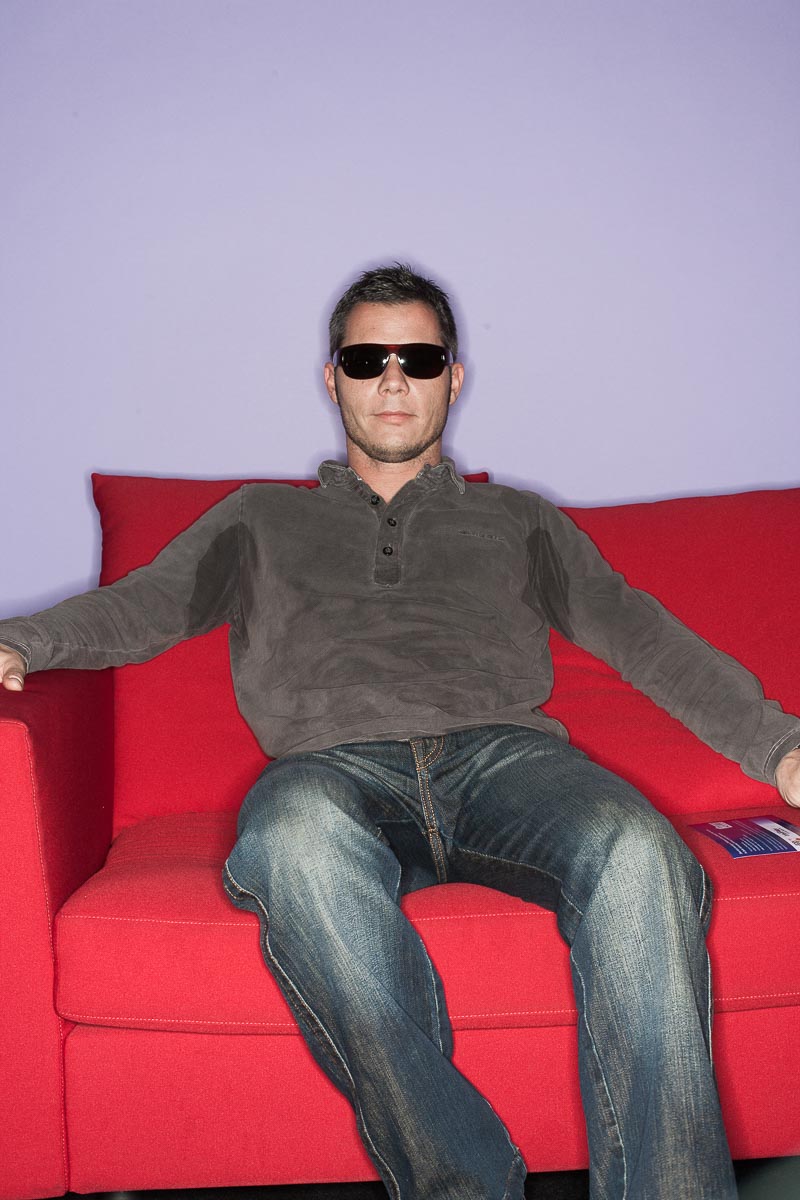 Poker Spieler mit Sonnenbrille auf einer roten Couch