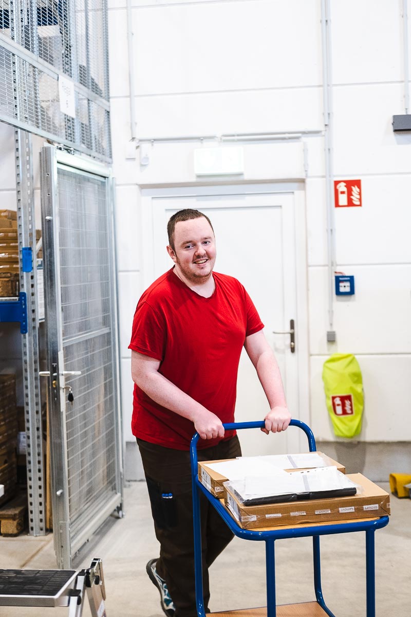 Ein Mitarbeiter der Lebenshilfe holt mit einem Wagen Material aus dem Lager