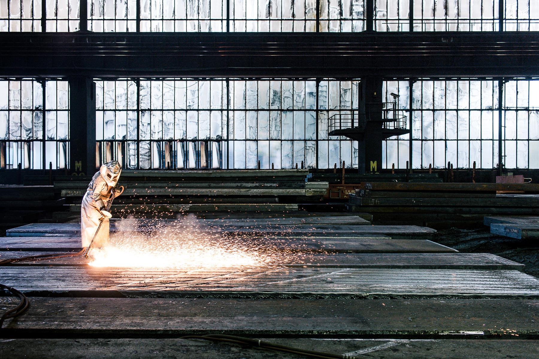 Stahlwerk von ThyssenKrupp Duisburg - Mitarbeiter in Schutzkleidung beim Flämen von Brammen