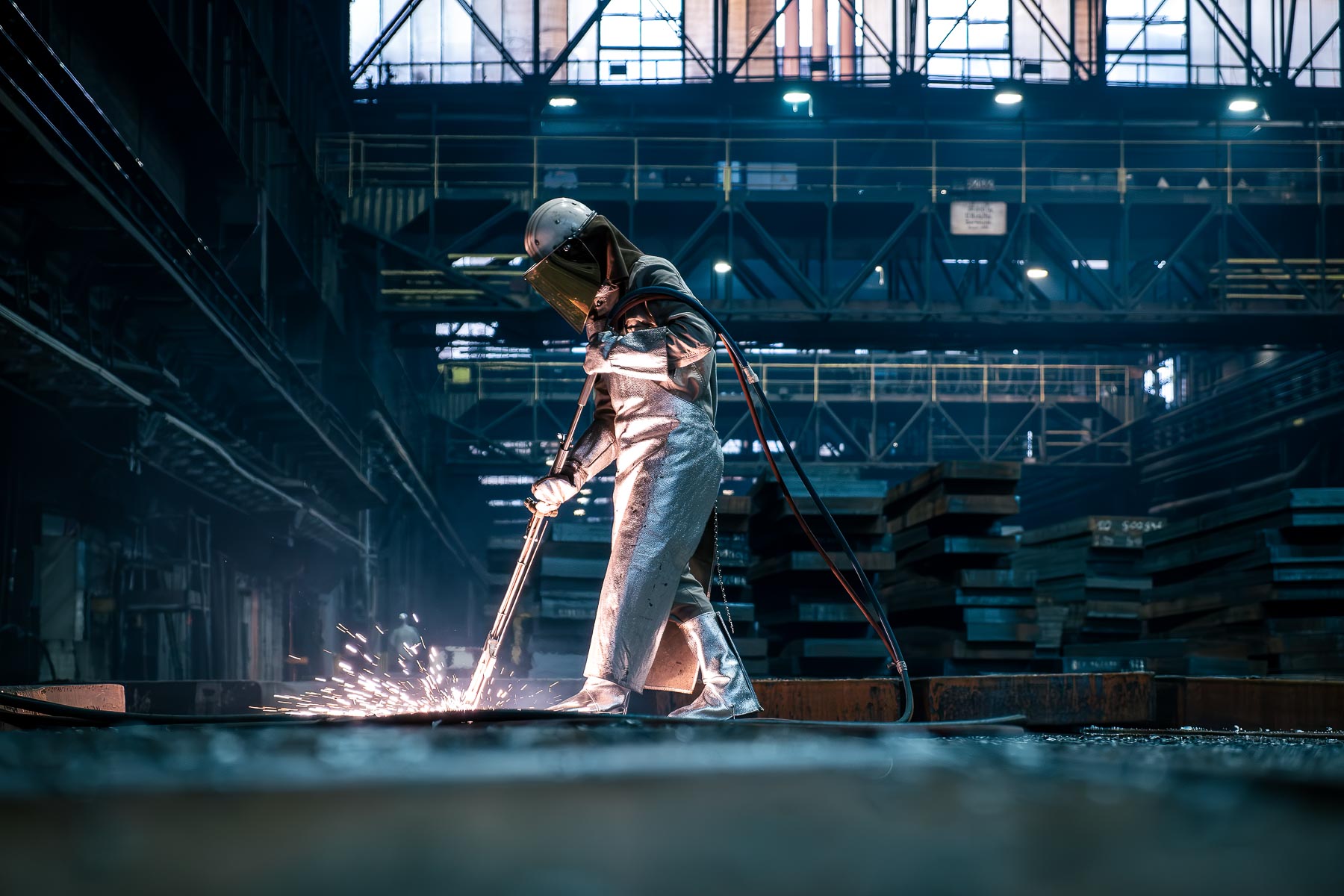 Stahlwerk von ThyssenKrupp Duisburg - Mitarbeiter in Schutzkleidung beim Flämen von Brammen