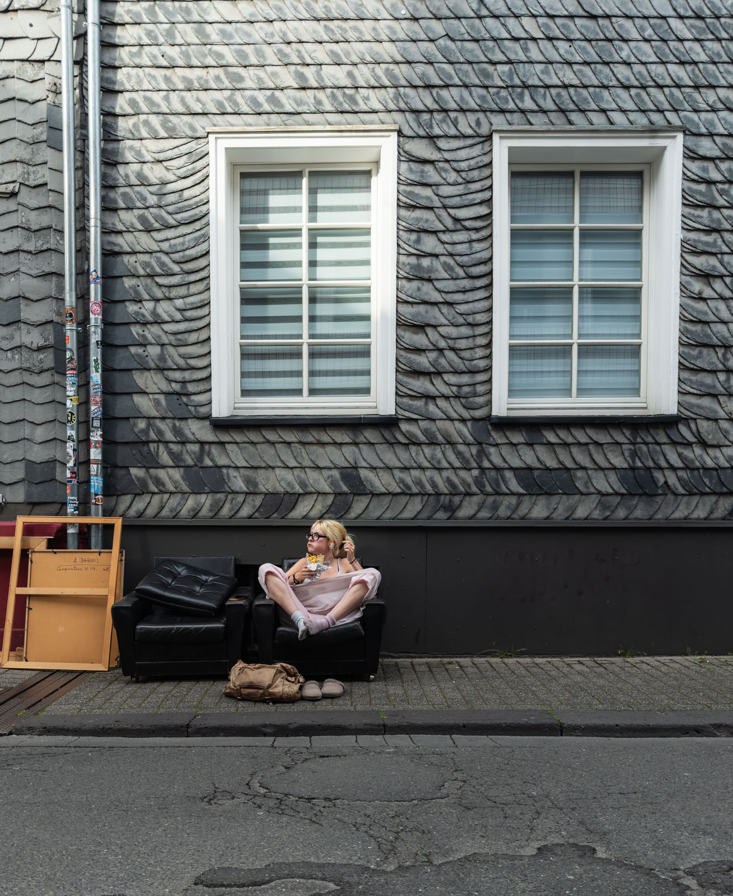 Eine Frau sitzt auf einer Couch vor einem Haus und isst 