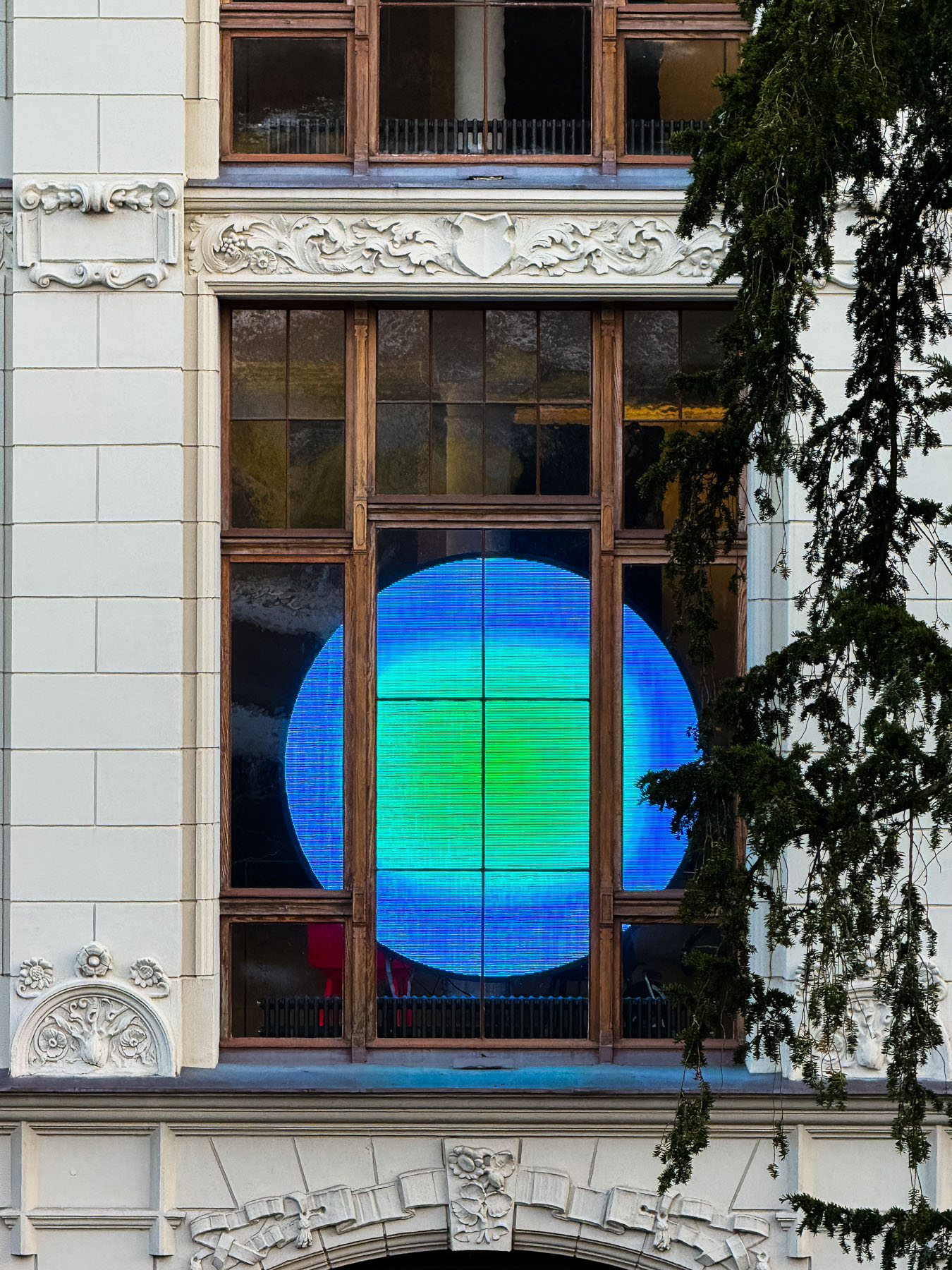 Fenster eines Gebäudes aus der Gründerzeit durch das man ein projiziertes Bild sieht