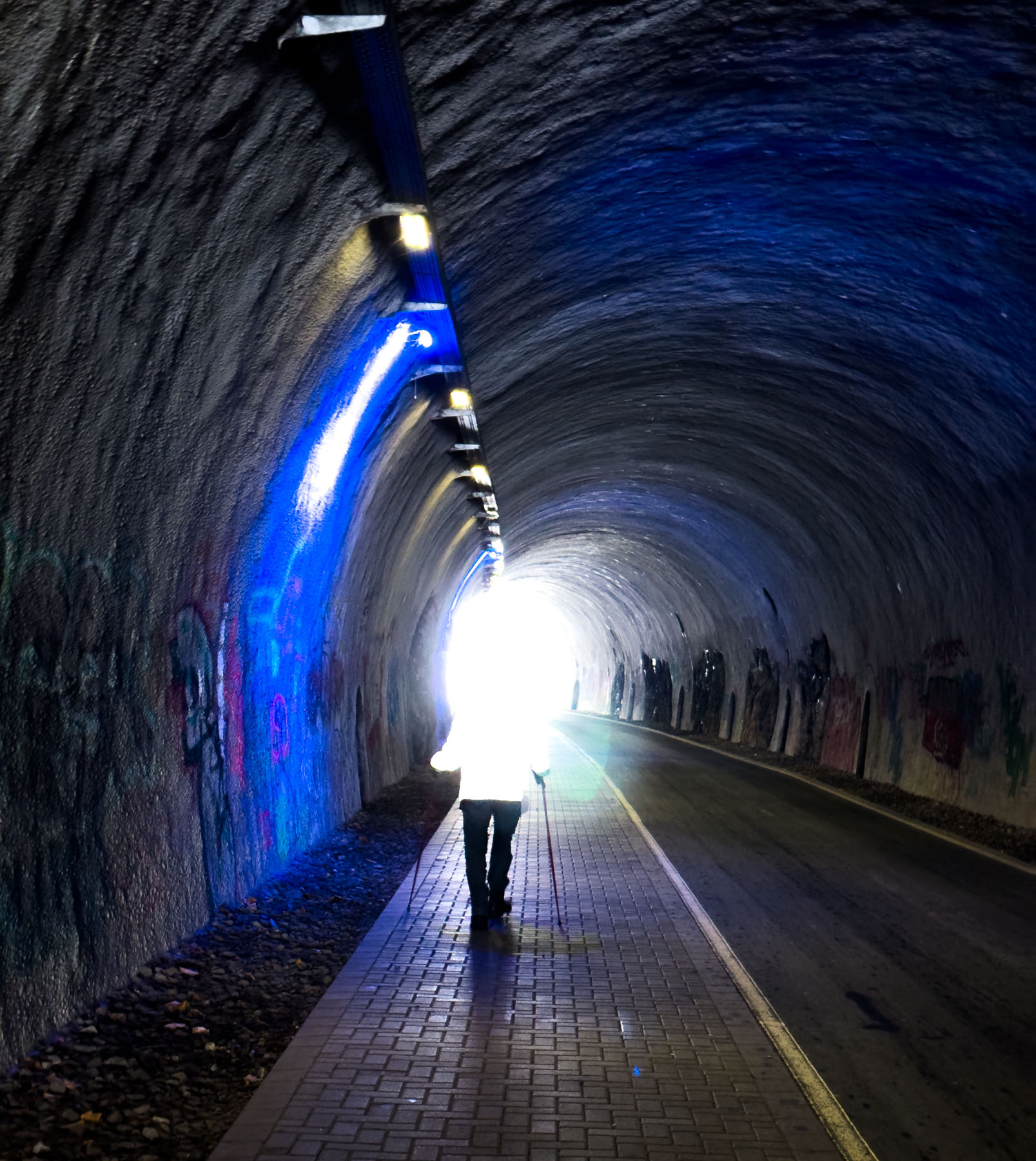 Eine Person mit Wanderstöcken geht durch einen Tunnel der Nordbahntrasse