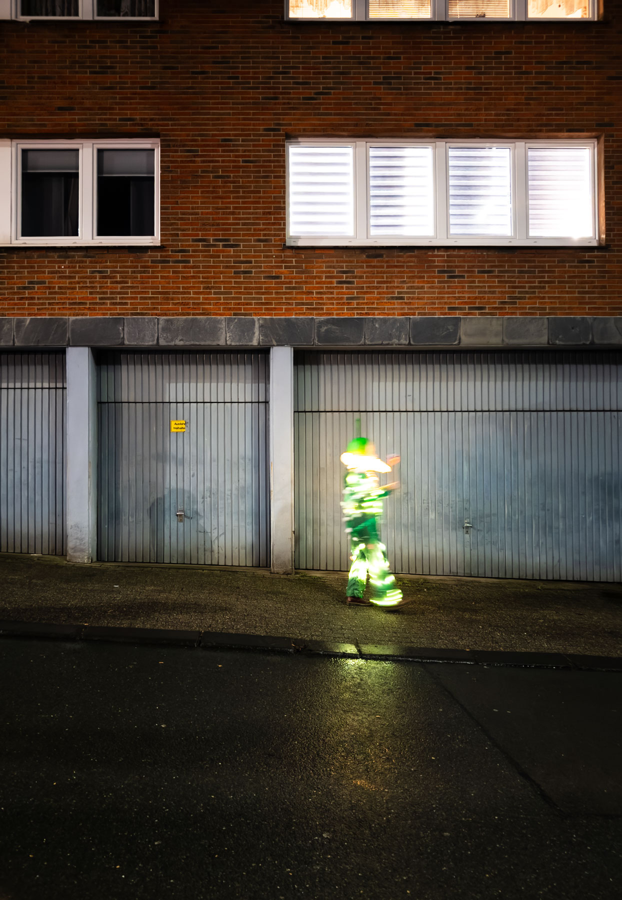 Eine Person mit umgehängten Lichterketten geht auf einem Bürgersteig, Lichterfest am Ostersbaum